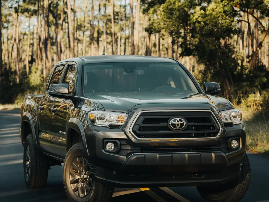 Dark green Toyota Tacoma TRD Off-Road double-cab pickup on a forest road