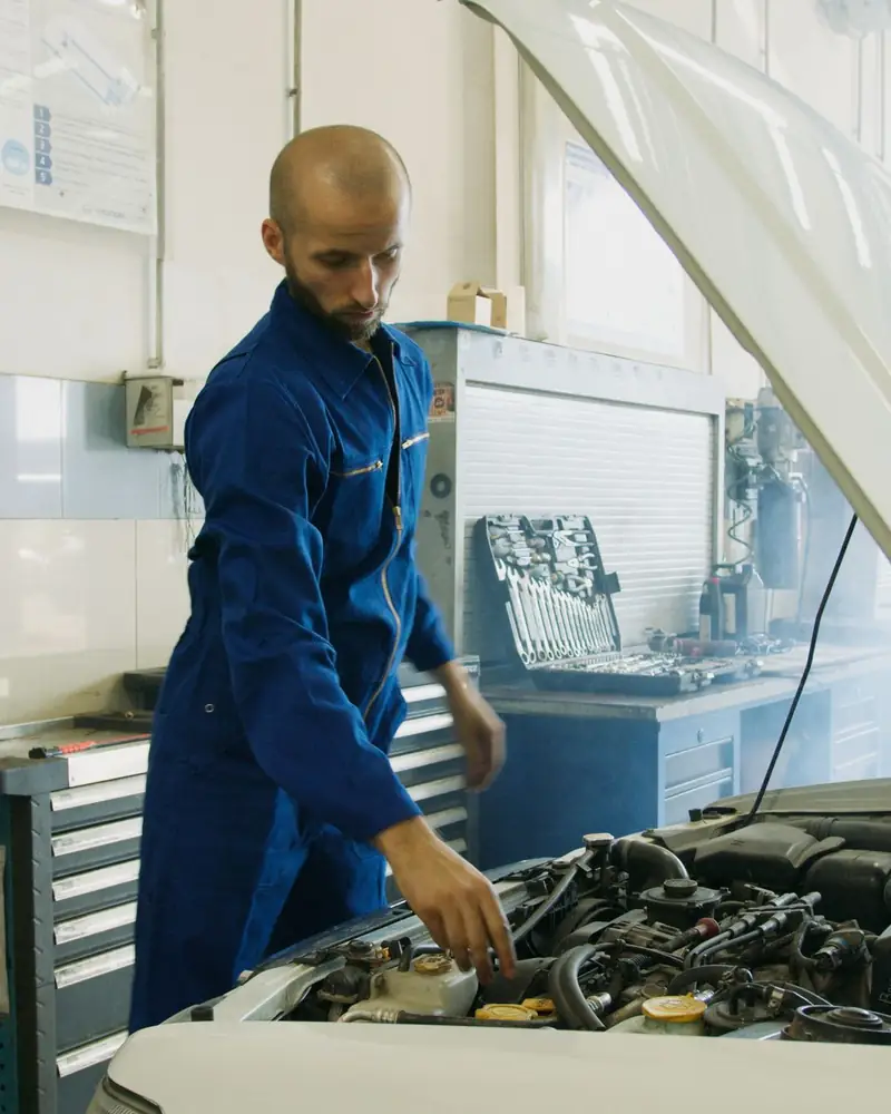 A technician checking over an engine bay with the bonnet raised